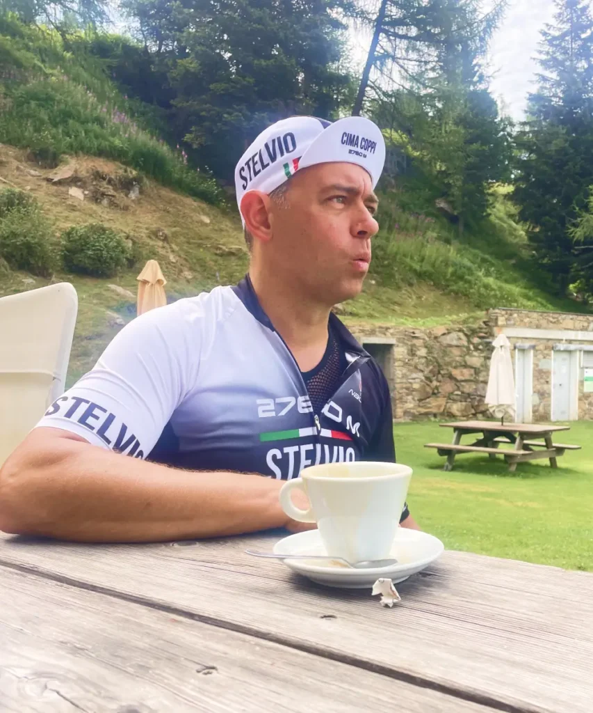 Cyclist sipping espresso at the Mortirolo climb wearing a Stelvio jersey