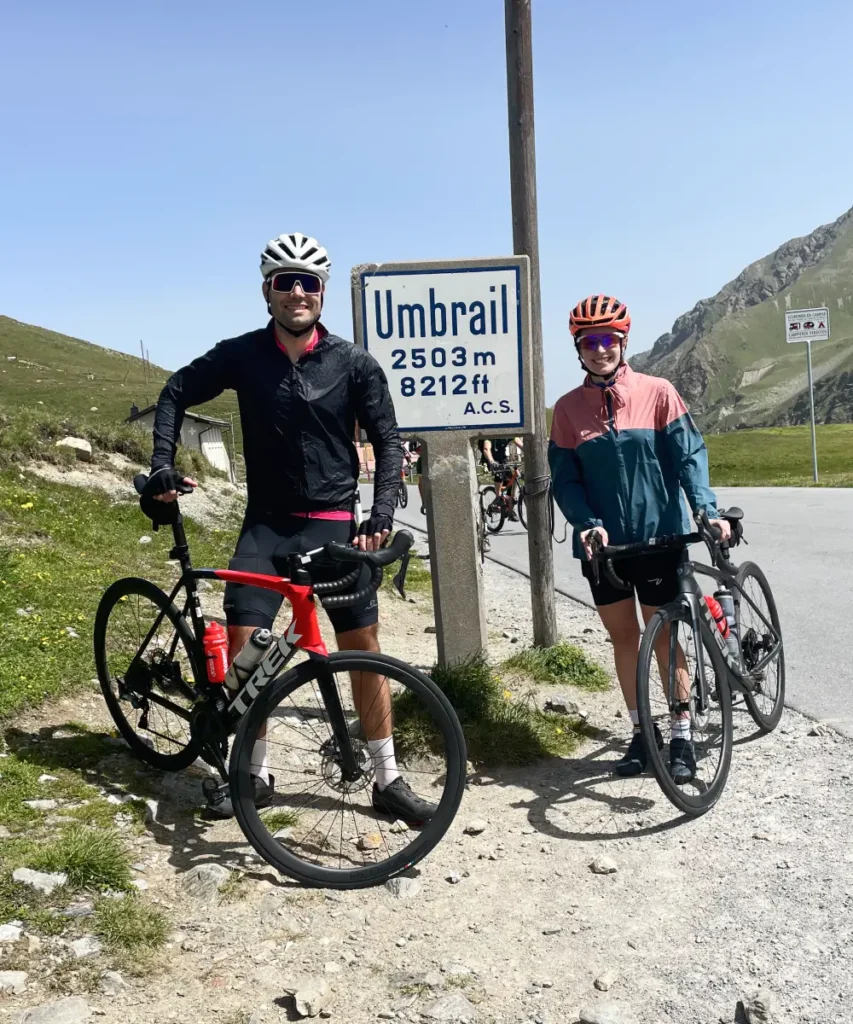 Cyclists posing at the Umbrail Pass sign connecting Switzerland and Italy