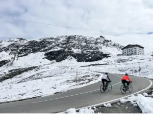 Two cyclists riding through snow-covered roads near the summit of the Stelvio Pass