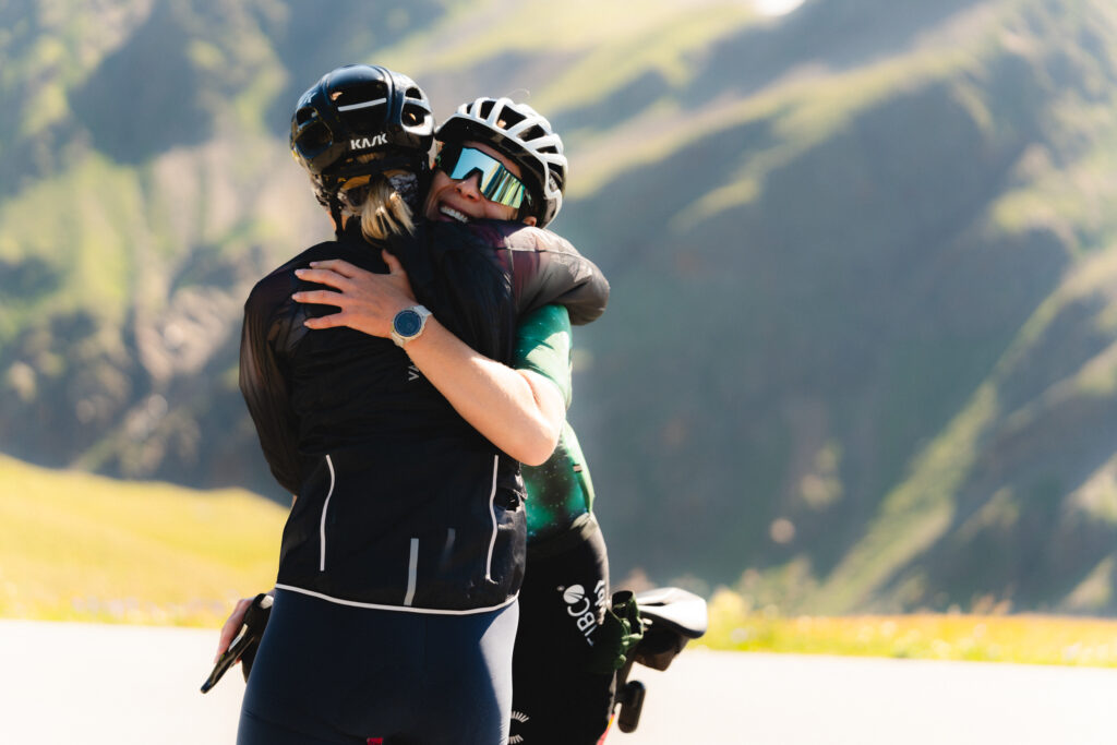 Two cyclists hug each others at the top of the Stelvio Pass